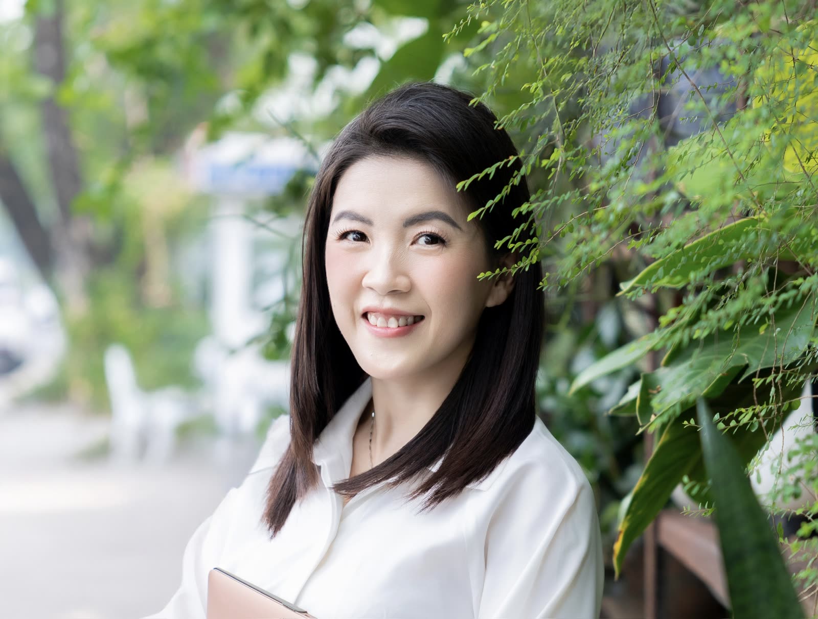 Người hướng dẫn workshop mỉm cười bên hàng cây xanh